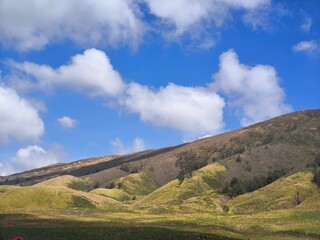 Landscape of rolling hills with vibrant green grass under a blue sky