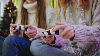 Two friends have a cozy gaming night, controllers in hand, dressed in warm sweaters, surrounded by festive decor that captures the holiday spirit of joy and togetherness