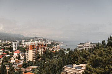 Obraz premium View of coastal city blending modern architecture with nature. The foreground showcases tall apartment buildings surrounded by dense greenery, creating vibrant contrast between urban life 