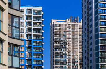 Modern buildings, walls and windows, reflections and sun rays. City view on a sunny day. 