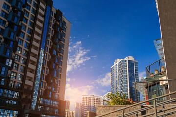 Obraz premium Modern buildings, walls and windows, reflections and sun rays. City view on a sunny day. 