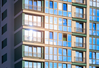 Modern buildings, walls and windows, reflections and sun rays. City view on a sunny day. 