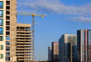 Construction cranes and new buildings, construction work of modern skyscrapers on a sunny day.