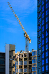 Construction cranes and new buildings, construction work of modern skyscrapers on a sunny day.