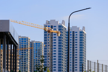Fototapeta premium Construction cranes and new buildings, construction work of modern skyscrapers on a sunny day.