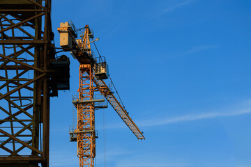 Naklejka premium Construction cranes and new buildings, construction work of modern skyscrapers on a sunny day.