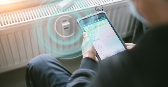 heating system engineer ist adjusting the digital w-lan network thermometer reader on a new thermal radiator.