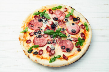 Pizza with mozzarella cheese , salami sausages , olives , and basil