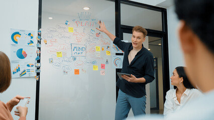 Fototapeta premium Professional male leader presents start up project by using mind map, colorful sticky notes and business statistic graph with confident while investor listening carefully. Immaculate.