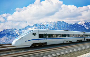 The high-speed train passes through the snow capped mountains