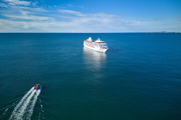 An excursion boat heads towards big cruise ship. Vacationing on a cruise