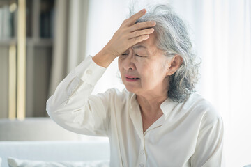 portrait a stressful senior woman suffering with headache alone at home,elderly,health care and medical,health insurance