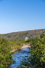 River flowing through tundra landscape with background of mountains, short summer in Finnmark, Norway. Northernmost part of continental Europe