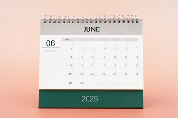 June 2025 desk calendar isolated in pink background.