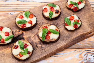 Italian mini pizza . Aubergine (eggplant ) with mozzarella cheese and basil . On rustic background