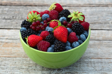 Mix of ripe colorful berries in bowl photography . Blueberry , strawberry , raspberry , blackberry and red currant . Top view