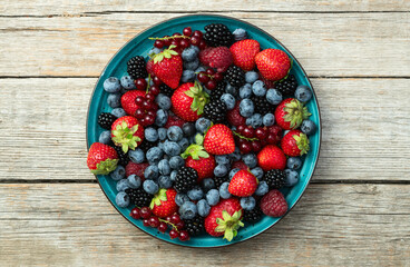 Mix of ripe colorful berries in bowl photography . Blueberry , strawberry , raspberry , blackberry and red currant . Top view