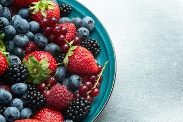 Mix of ripe colorful berries in bowl photography . Blueberry , strawberry , raspberry , blackberry and red currant . Top view