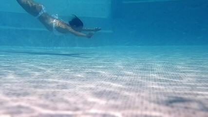 A woman swims gracefully underwater in a transparent pool, her movements smooth and serene. This breathtaking scene evokes a feeling of calm and freedom. Spa and travel concept.