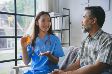 Young female doctor holding medicine bottle explaining prescription to senior patient sitting on sofa at home