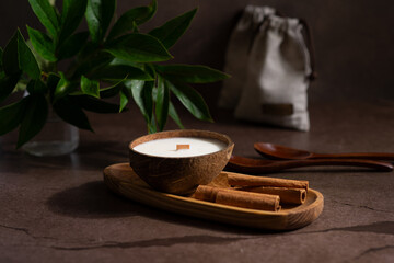 Soy candle in coconut on dark background on wooden table