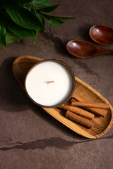 Soy candle in coconut on dark background on wooden table