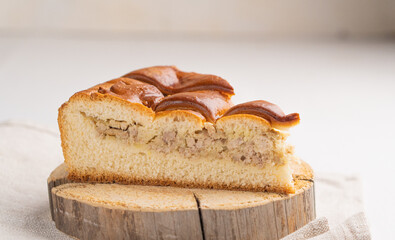 A piece of yeast pie with meat filling on a light background