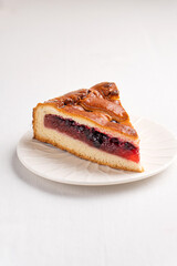 A piece of yeast pie with berry filling on a light background