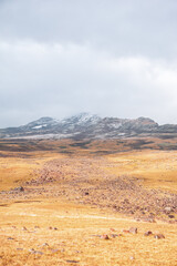 Rugged mountain landscape with golden tundra and cloudy sky