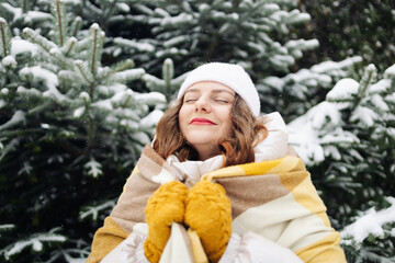 Winter woman happy enjoying snow falling on face outdoor forest nature. Young beautiful Caucasian female breathing fresh air at seaside in a snowy park