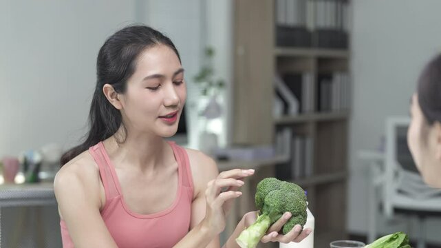 Nutritionist holding broccoli explains the benefits of healthy food to a client, emphasizing the importance of a balanced diet and nutritious eating for overall wellness