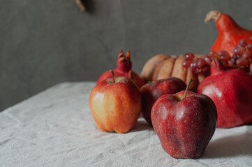 Autumn still life harvest Thanksgiving table serving with pumpkins pommegranates and grapes on linen cloth with candles modern minimalist scandinavian sustainable eco styling