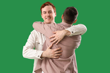 Male friends hugging on green background