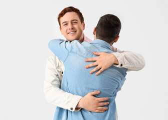 Male friends hugging on white background