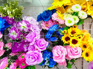 Roses, orchids, and various other flowers displayed on a wall shelf.
