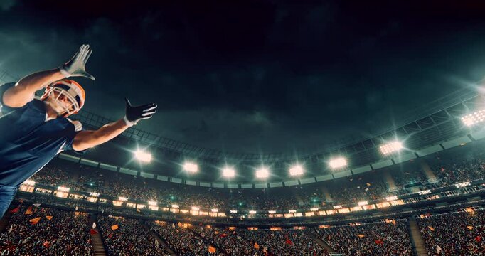 This video captures a dramatic moment in an American football game as a player in a blue jersey dives mid-air to catch the ball. The bright stadium lights and cheering crowd amplify the intensity and 