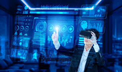 Project manager with VR goggles pointing financial chart and glowing blue light at office. Skilled businessman checking and planning marketing strategy by using data from augmented reality. Ingenuity.