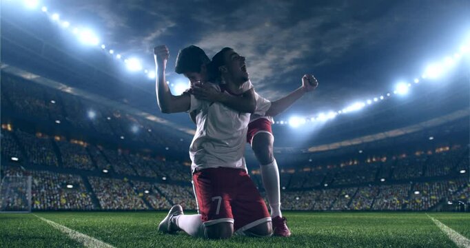 Two football players selebrating a goal. Professional stadium with animated crowd at night.