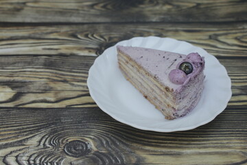 A piece of Mille Crepes with blueberry cheesecake flavor on a small white plate.