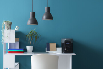 Portable power station with laptop on desk near blue wall in office