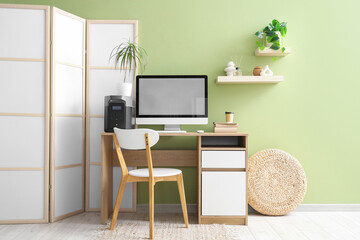 Interior of office with workplace, portable power station and folding screen