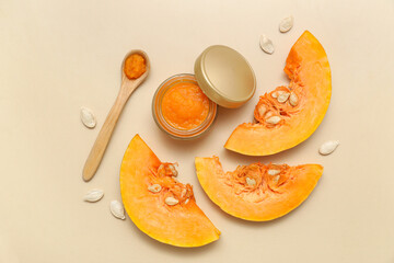 Jar of cosmetic pumpkin mask with seeds on beige background