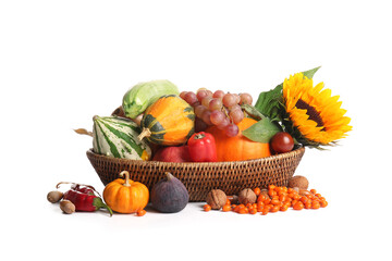Wicker basket with different fresh vegetables, fruits and sunflower on white background. Harvest festival