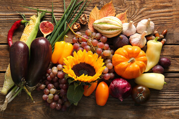 Different fresh vegetables with fruits and sunflower on wooden background. Harvest festival