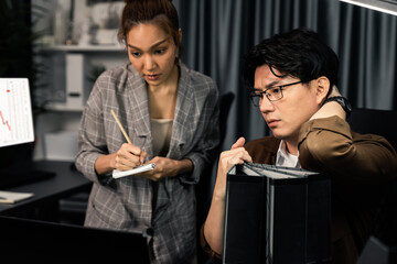 Managers discussing on document paperwork together for business planning on market share data at over late night time at modern home office, working on startup company deadline project job. Infobahn.