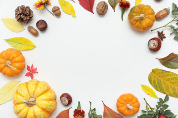 Frame made of autumn leaves with beautiful flowers, different nuts and fresh pumpkins on white background