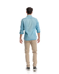 casual young man seen from behind in blue denim shirt and chino pants