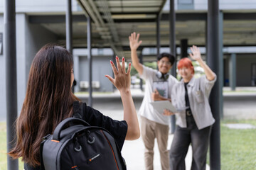 Young woman waves goodbye to friends on a university campus, radiating happiness and togetherness...