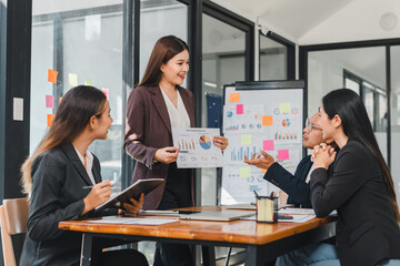 businesswoman presents data charts to colleagues in modern office setting, showcasing teamwork and collaboration