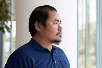 Portrait of pensive, thoughtful middel aged Asian man thinking, planning, finding a good idea